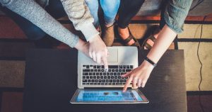 Image of three casually dressed people sitting around a laptop pointing to the screen: This article is about content marketing.