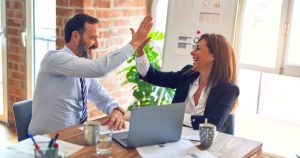 Picture of a man and a woman at a desk give each other a high five. Another digital marketing success