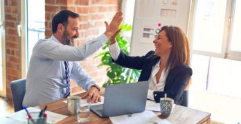 Picture of a man and a woman at a desk give each other a high five. Another digital marketing success