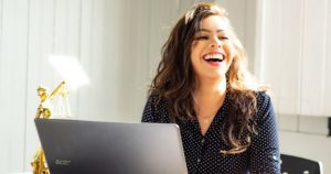 Picture of a woman at her laptop Laughing. Making money
